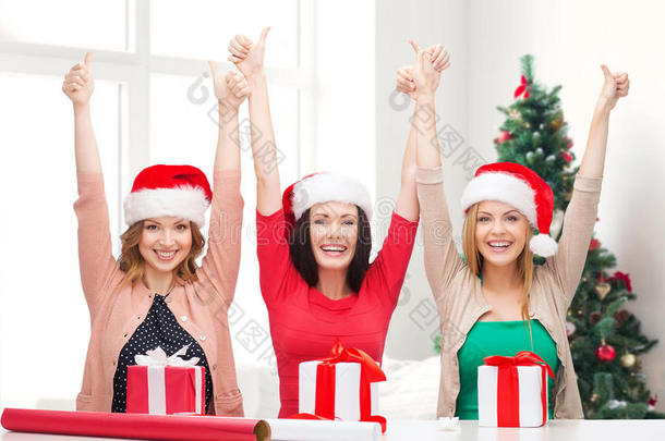 微笑的女人戴着圣诞老人的帽子包装礼物