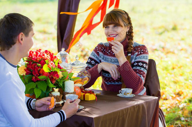 美丽的年轻夫妇在秋天公园野餐。快乐的家庭户外活动。微笑的男女在公园里放松。关系。