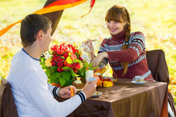 美丽的年轻夫妇在秋天公园野餐。快乐的家庭户外活动。微笑的男女在公园里放松。关系