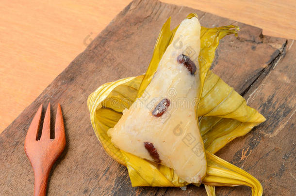 打开的泰国甜点糯米饭包裹在木质背景上的香蕉叶。