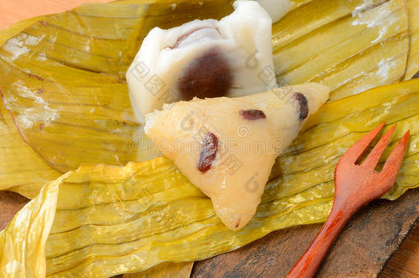 打开的泰国甜点<strong>糯米饭</strong>包裹在木头背景上的香蕉叶