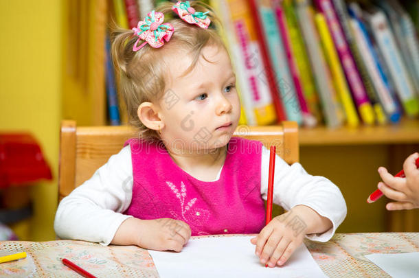 幼儿园的小女孩在饭桌上用<strong>彩色铅笔画</strong>画