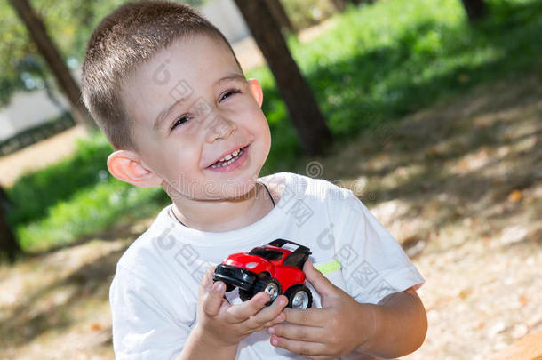 夏天，可爱的小男孩在公园里玩玩具车。
