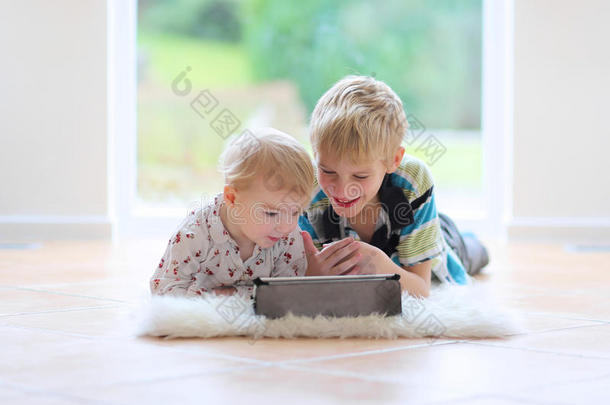 兄妹俩在室内玩平板电脑