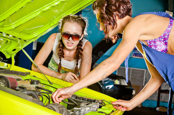 两个女汽车修理工在修理一辆汽车