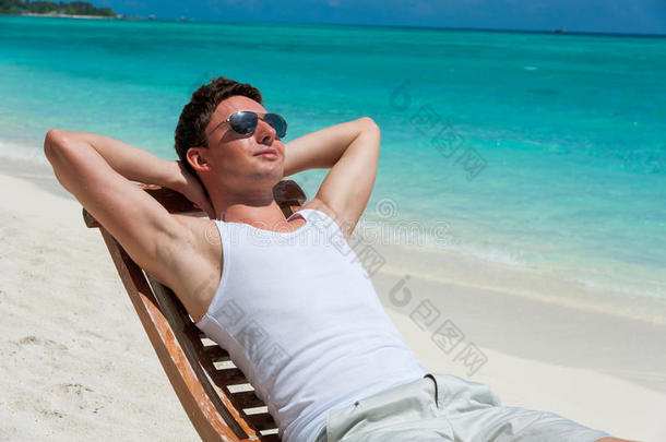 坐在椅子上的男人在<strong>海边</strong>的海滩上<strong>晒太阳</strong>