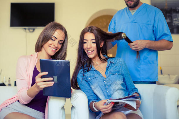 美女在平板电脑上展示发型师，例如美发沙龙的发型。