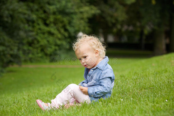 可爱的小女孩坐在户外的草地上