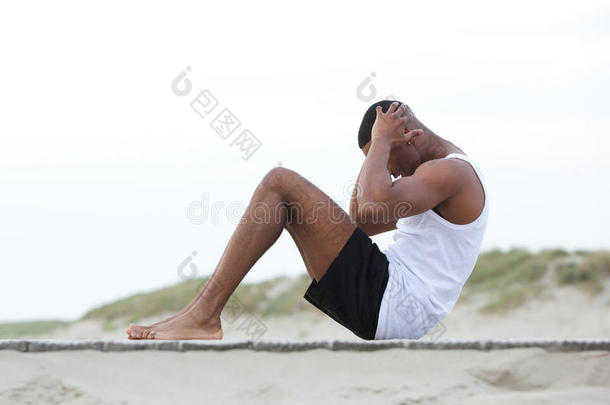 一个年轻人在海滩上做仰卧<strong>起坐</strong>运动