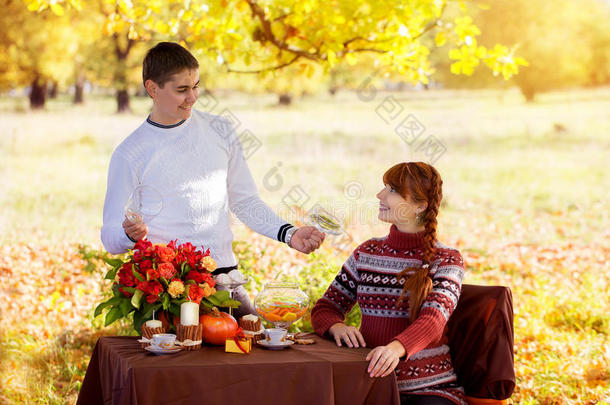 美丽的年轻怀孕夫妇在秋天公园野餐。哈