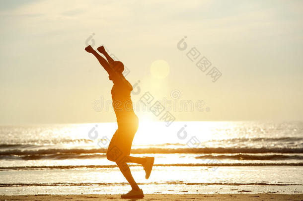 一个人举着胳膊在沙滩上奔跑