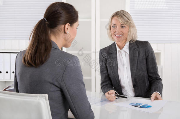 坐在办公桌旁的两位女商人：顾客和顾问<strong>谈话</strong>