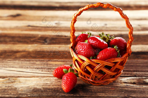 草莓放在棕色木质背景的篮子里。