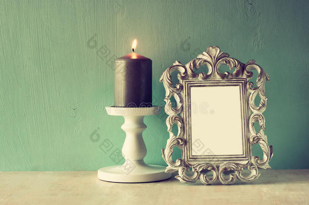 古色古香的古典画框和木桌上燃烧的蜡烛的低调形象。过滤后的图像