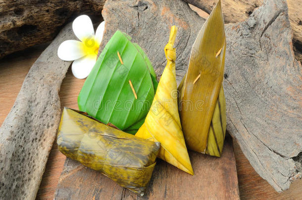 泰国甜点糯米饭包裹在木头背景上的香蕉叶。
