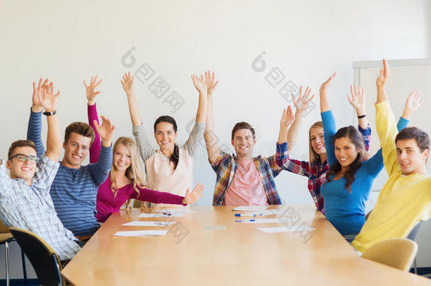 一群微笑的学生在办公室举手