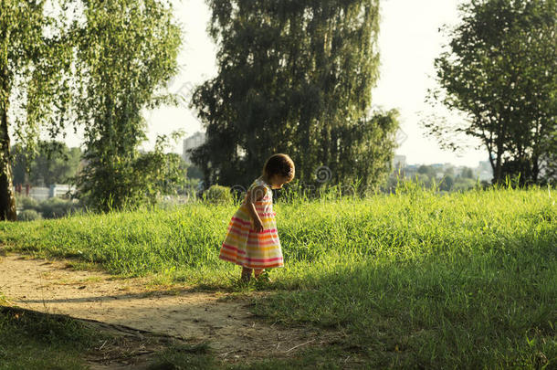 穿着<strong>漂亮衣服</strong>的可爱小女孩在夏日的田野上散步