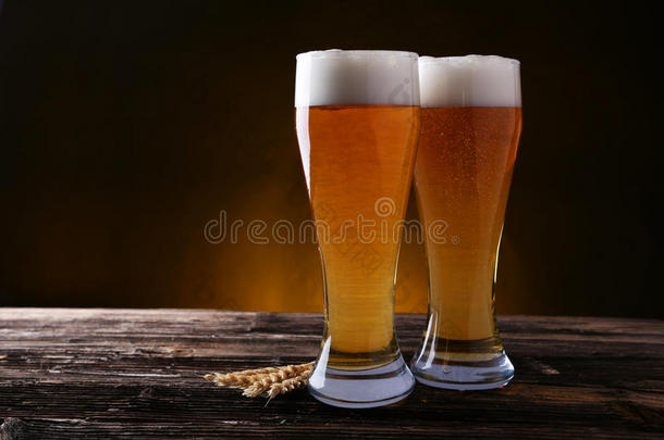 两杯啤酒，背景是棕色的木头。