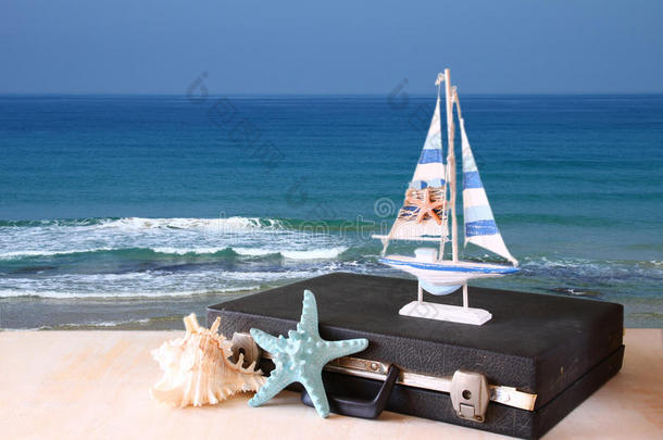 老式的箱子，旧船玩具和海星在海景前面。旅游概念