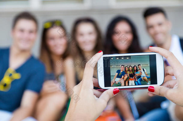 一群朋友在街上用智能手机拍照。