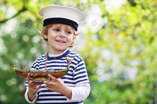 快乐的孩子穿着船长制服在玩玩具船