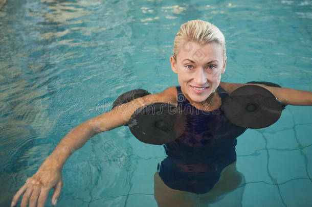 女游泳运动员在游泳池里用泡沫哑铃健身