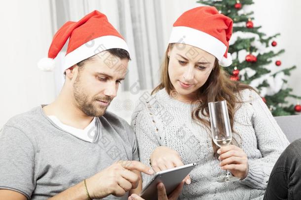 快乐的年轻夫妇圣诞节用平板电脑