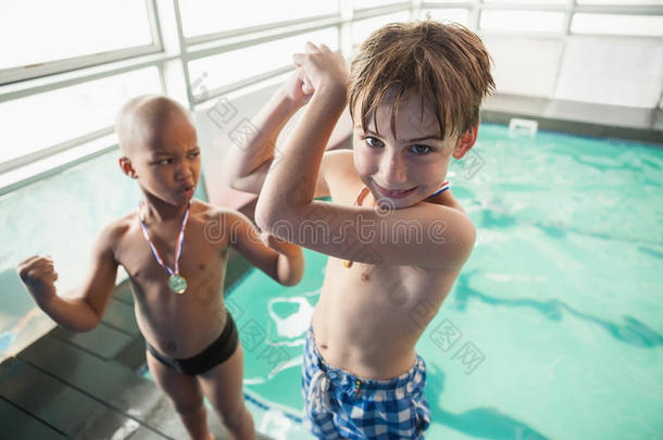 小男孩拿着奖牌站在游泳池旁