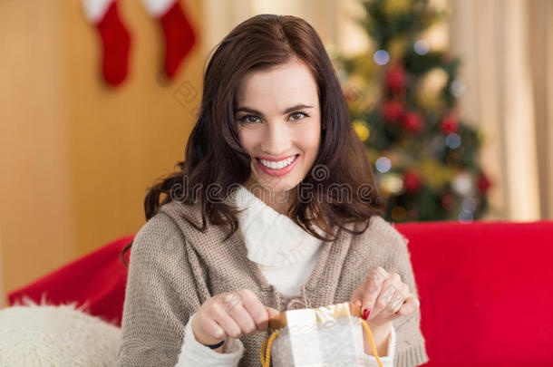 圣诞节时，黑发女人在沙发上打开礼物