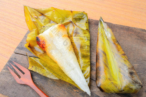 打开的<strong>泰国</strong>甜点<strong>糯米饭</strong>包裹在木头背景上的香蕉叶