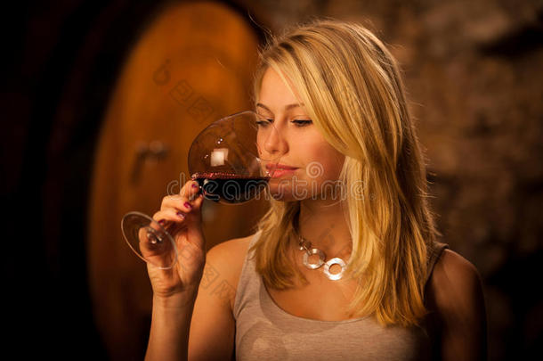 年轻漂亮的金发女子在酒窖里品尝红酒