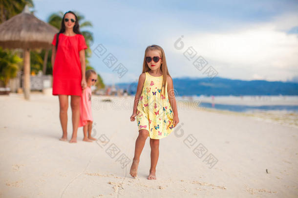 日落时，母亲和她的两个孩子在异国风情的海滩上