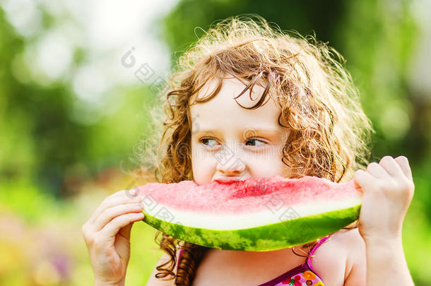 快乐的小女孩在夏日公园吃西瓜。