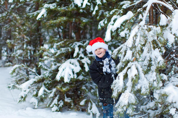 冬天森林里戴着圣诞老人帽的快乐男孩。
