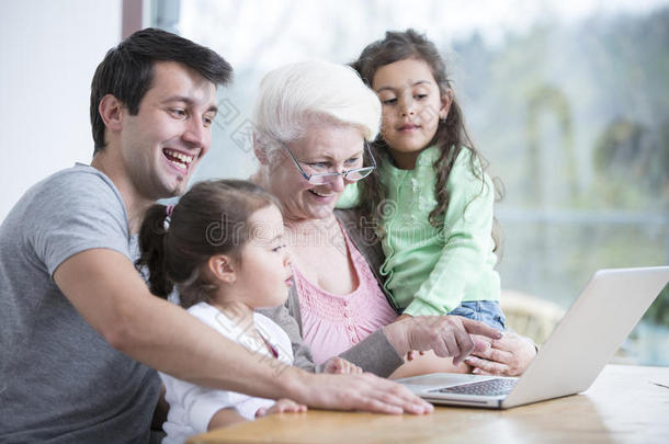 三代幸福家庭在家里用笔记本电脑吃饭