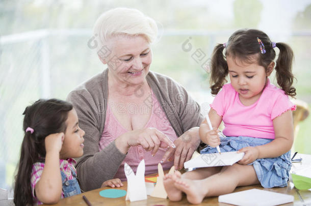 快乐的老太太在家里帮助孙女们<strong>做手工</strong>艺品