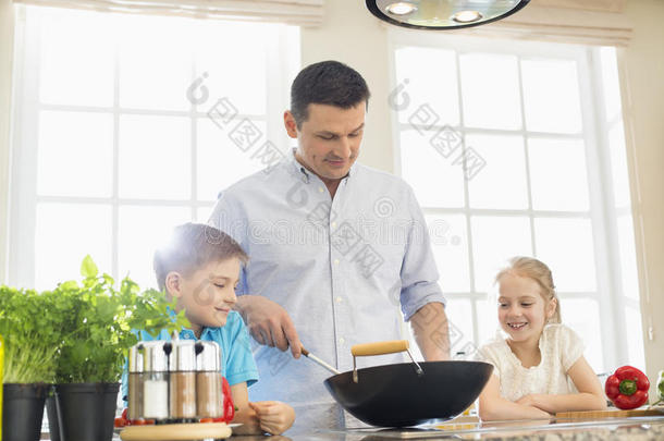 孩子们看着父亲在厨房里准备食物