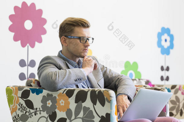中年商人在创意办公室的扶手椅上使用笔记本电脑