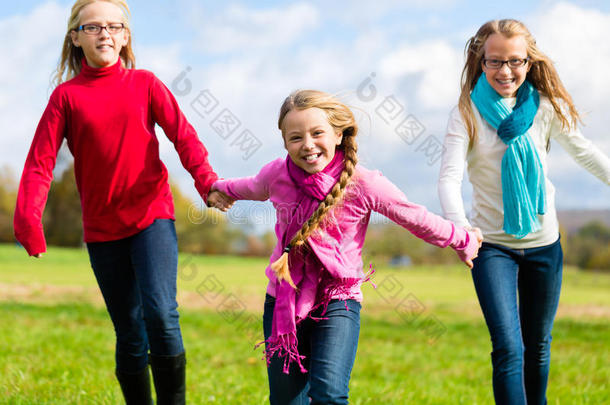 女孩们在秋天或秋天的公园里奔跑