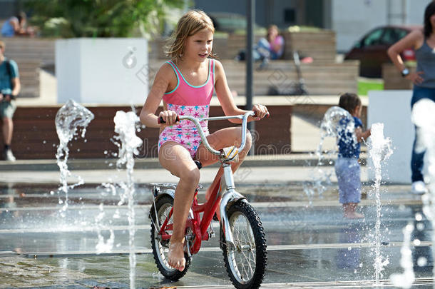 小女孩骑着他的自行车在喷泉间穿梭