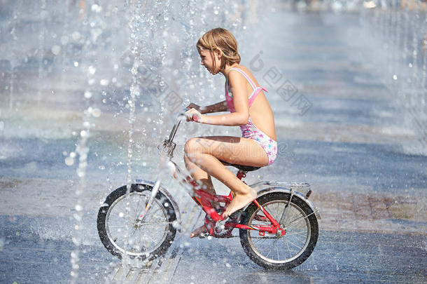 小女孩骑着他的自行车在喷泉间穿梭