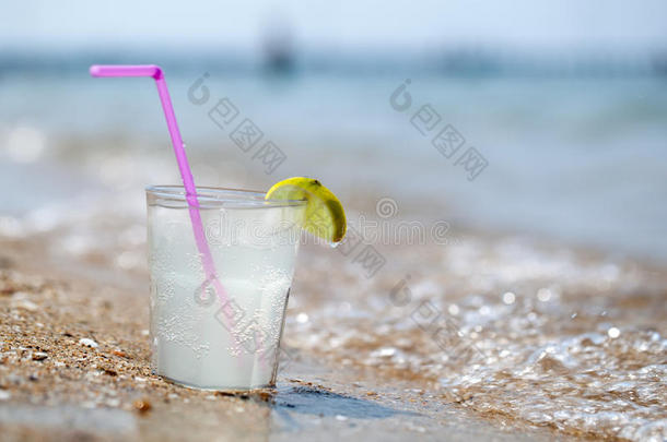 海边沙滩上的一杯柠檬水或水