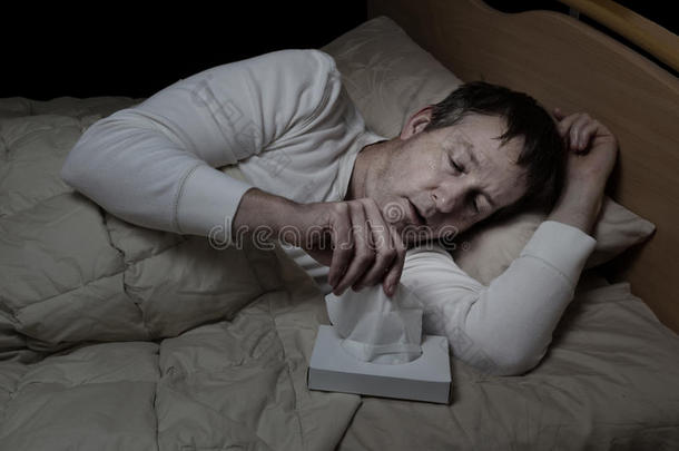 生病的成年男子在床上用纸巾