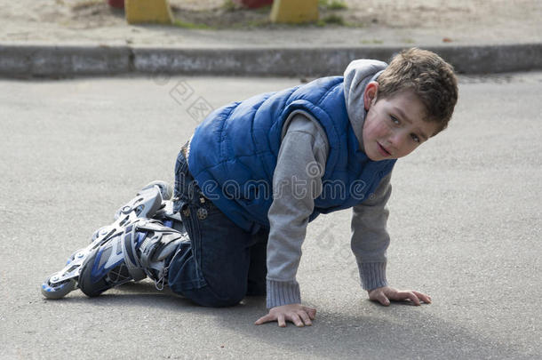 春天男孩滑旱冰，摔倒在路上。