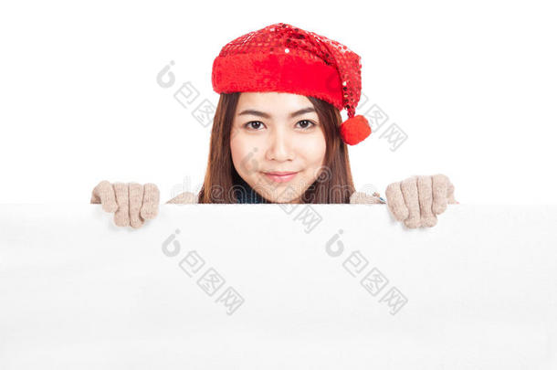 亚洲女孩戴着红色圣诞帽从空白横幅后面偷窥