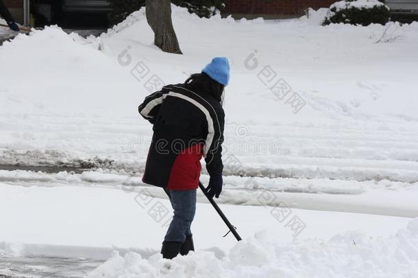 正在车道上铲雪的女士