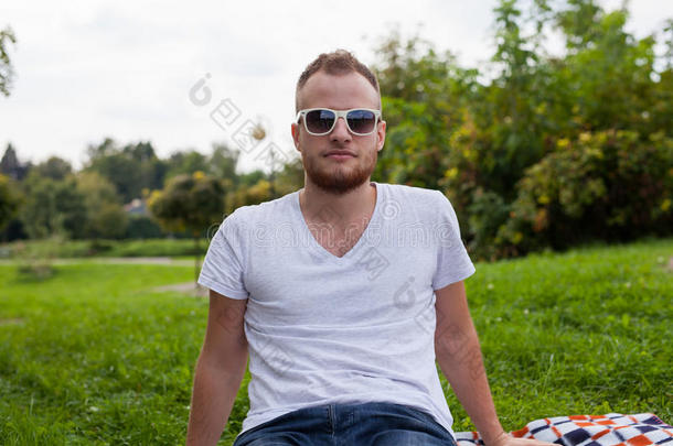 有胡子的年轻人的画像。在阳光明媚的夏天或春天，在公园外微笑的白人男子