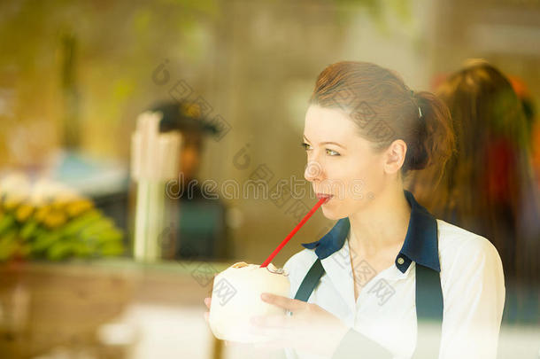 女人喝着椰子汁，望着外面的街道