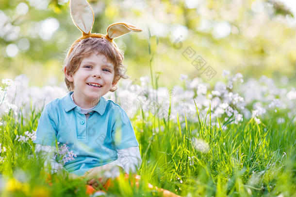 可爱快乐的小男孩戴着复活节兔子耳朵在春天的绿色