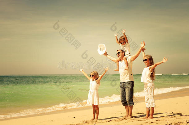 快乐的一家人白天在沙滩上散步。
